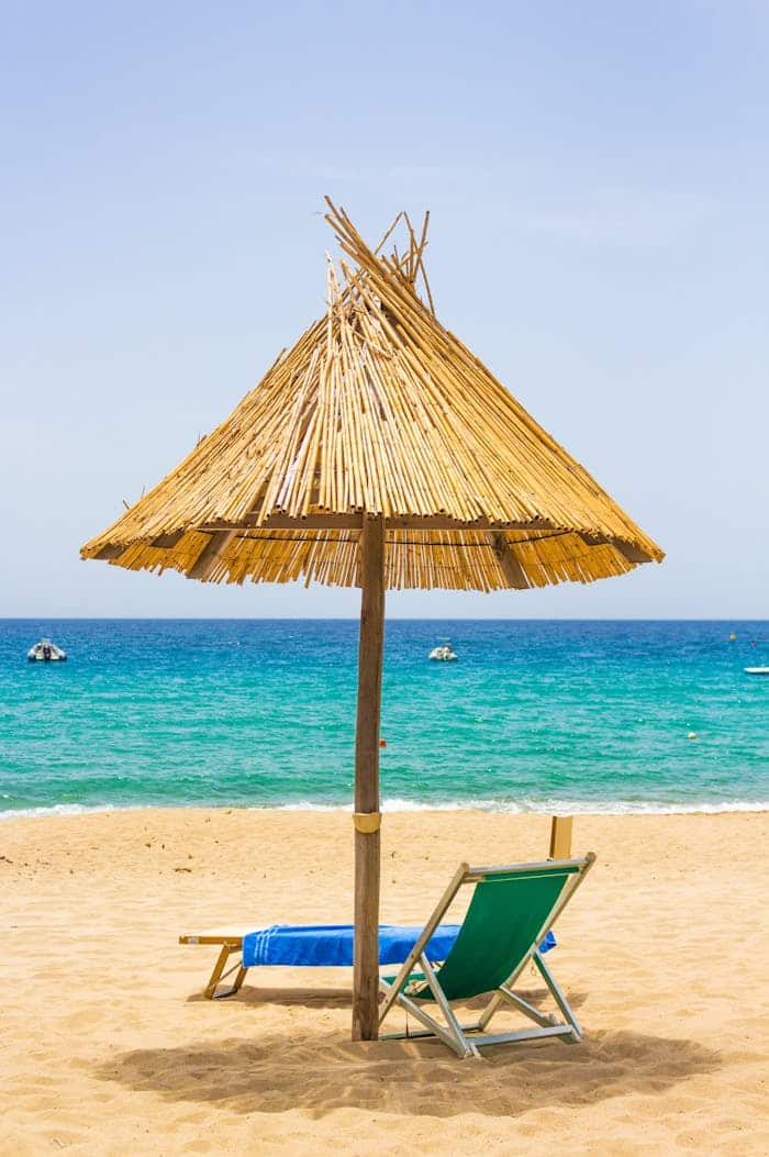 Serene beach scene in Sardinia, Italy featuring a sunshade and lounge chairs by turquoise waters.